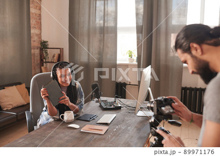 Horizontal selective focus shot of modern cameraman shooting video of young female influencer, copy space 89971176