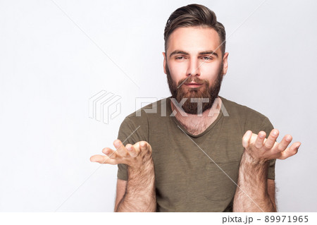 I don't know! Portrait of confused bearded man with dark green t shirt against light gray background. studio shot. . I don't know! Portrait of confused bearded man with dark green t shirt against light gray background. studio shot. . 89971965