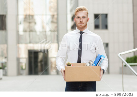 Youre fired. Unhappy bearded business man going out with cardboard, looking at camera and feeling looser. Outdoor Youre fired. Unhappy bearded business man going out with cardboard, looking at camera and feeling looser. Outdoor 89972002
