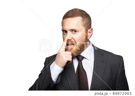 Closeup portrait of handsome serious businessman with facial beard in black suit standing and touching his nose and showing lie gesture. indoor studio shot isolated on white background. Closeup portrait of handsome serious businessman with facial beard in black suit standing and touching his nose and showing lie gesture. indoor studio shot isolated on white background. 89972003