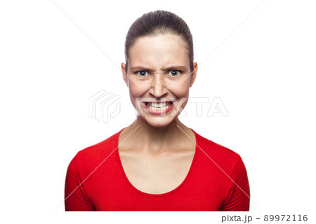 Portrait of worried angry woman in red t-shirt with freckles. looking at camera and screaming, studio shot. isolated on white background. 89972116