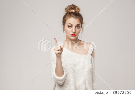 Teacher blonde woman finger up and looking seriously at camera. Studio shot, isolated on gray background Teacher blonde woman finger up and looking seriously at camera. Studio shot, isolated on gray background 89972250