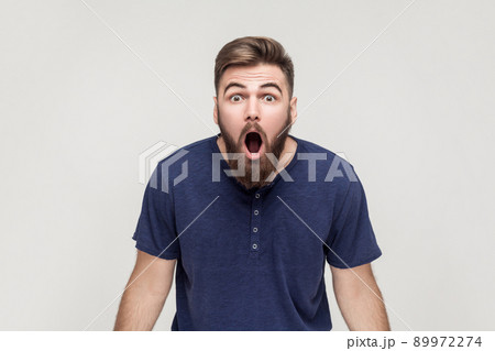 Unbelievable news! Young adult crazy man with opened mouth looking at camera. Studio shot, gray background 89972274