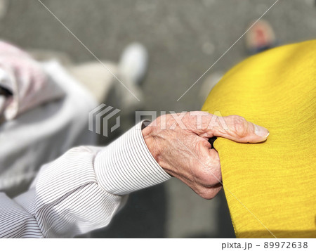 黄色い洋服をつかむ高齢女性の手 89972638