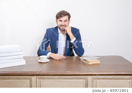 Technology, people and business concept - handsome man with beard and brown hair and blue suit and tablet pc computer and some books looking at camera with smile in the office. .Isolated on white Technology, people and business concept - handsome man with beard and brown hair and blue suit and tablet pc computer and some books looking at camera with smile in the office. .Isolated on white 89972801