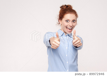 Happy cheerful redhead woman showing thumb up and toothy smile. Isolated studio shot on gray background Happy cheerful redhead woman showing thumb up and toothy smile. Isolated studio shot on gray background 89972946