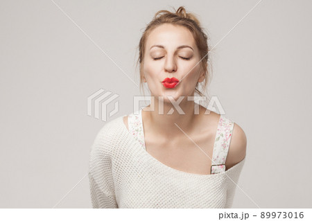 Closeup portrait of romantic woman send air kiss at camera. Studio shot, isolated on gray background Closeup portrait of romantic woman send air kiss at camera. Studio shot, isolated on gray background 89973016