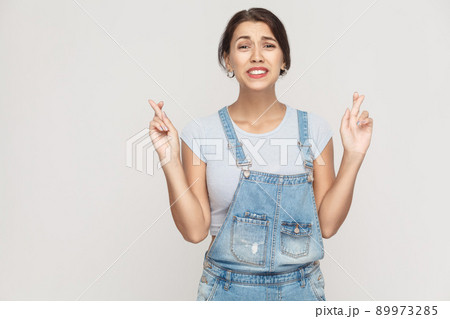 The very cunning woman, crossing fingers for good luck, hoping wishes will come true, looking up slyly. Indoor, studio shot 89973285