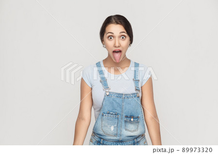 Happiness asian woman with big eyes and tongue out. Indoor shot on gray background studio shot Happiness asian woman with big eyes and tongue out. Indoor shot on gray background studio shot 89973320