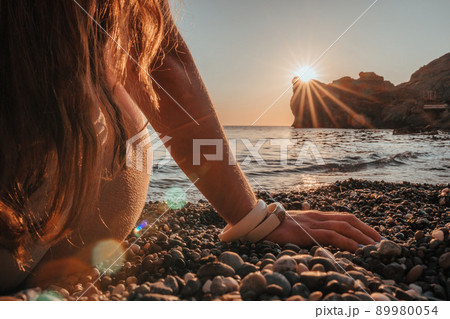 Young woman with long hair in white swimsuit and boho style braclets practicing outdoors on yoga mat by the sea on a sunset. Women's yoga fitness routine. Healthy lifestyle, harmony and meditation Young woman with long hair in white swimsuit and boho style braclets practicing outdoors on yoga mat by the sea on a sunset. Women's yoga fitness routine. Healthy lifestyle, harmony and meditation 89980054