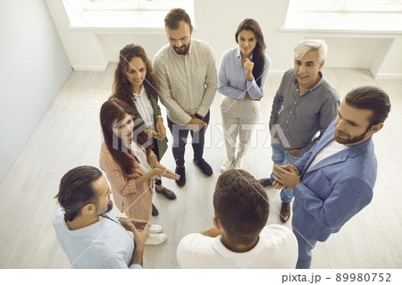 Group of people listening to business coach while standing in office during workshop 89980752