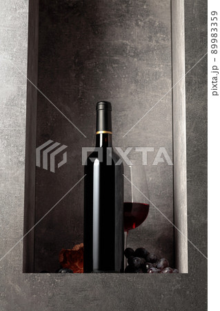 Bottle and glass of red wine with blue grapes. 89983359
