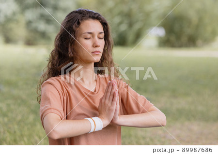 woman with curly hair meditates in a park. yoga and meditation for mental and physical health 89987686
