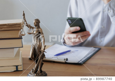 male lawyer in a white shirt and glasses consults a client online. statuette of the goddess of justice Themis on the table male lawyer in a white shirt and glasses consults a client online. statuette of the goddess of justice Themis on the table 89987740