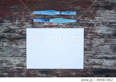 White paper sheet and water brushes on wooden background. White paper sheet and water brushes on wooden background. 89987862