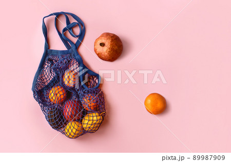 Net bag with fruit on bright background. Zero waste and ecology conservation concept. Fresh apples, tangerines, avocado and pomegranate in a reusable eco friendly shopping bag 89987909