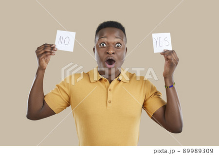 Funny confused young man holding YES and NO sticky notes and trying to make a choice 89989309