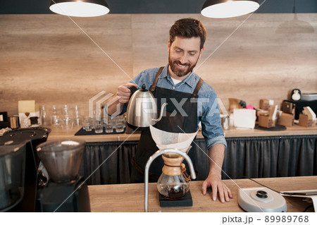 Smiling Barista pouring water to make coffee using manual drip brewer Smiling Barista pouring water to make coffee using manual drip brewer 89989768