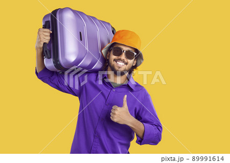 Happy Indian man going on holiday trip, carrying suitcase, smiling and giving thumbs up 89991614