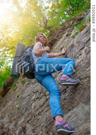 A young woman is engaged in rock climbing. Leisure and active sports. Light. Bottom view 89992031