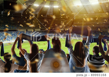 Win. Back view of football, soccer fans cheering their team with state flags and scarfs at crowded stadium at evening time. Concept of sport, support, competition. Out of focus effect Win. Back view of football, soccer fans cheering their team with state flags and scarfs at crowded stadium at evening time. Concept of sport, support, competition. Out of focus effect 89993168