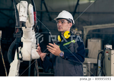 Young factory worker working with adept robotic arm 89995093
