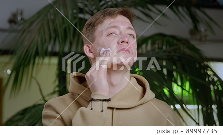 Close-up of a young man with pimples on his face. The guy is sad and washes the foundation off his face. Close-up of a young man with pimples on his face. The guy is sad and washes the foundation off his face. 89997735