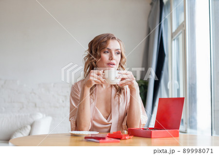 Delighted woman with coffee and chocolate at home in the morning Delighted woman with coffee and chocolate at home in the morning 89998071