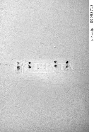 Hole and dowels in an old dirty white wall. 89998718