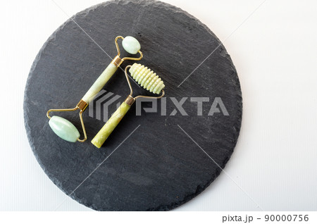 Two different stone rollers for skin care. Green stones on black stone. Copy space. Two different stone rollers for skin care. Green stones on black stone. Copy space. 90000756