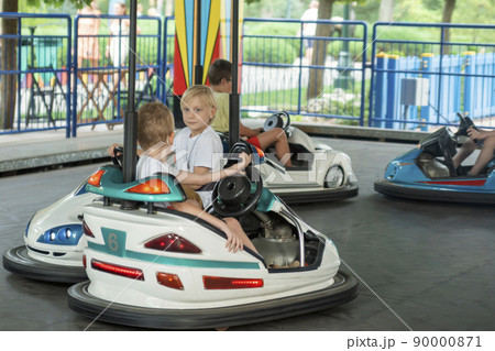 Children driving bumper car in an amusement park. Boys drive toy electric cars, funny vacations Children driving bumper car in an amusement park. Boys drive toy electric cars, funny vacations 90000871