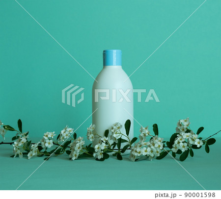 A bottle for cosmetic products without a label with a flower branch at the bottom. Facial skin care concept. 90001598