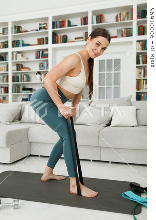 Woman during her fitness workout at home with rubber resistance band Woman during her fitness workout at home with rubber resistance band 90001695