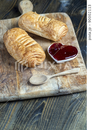 puff pastry with red strawberry jam on a wooden table 90002113