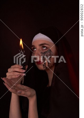 Portait of gothic girl looks up and holding wax candle. 90002832