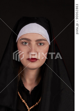 Front portrait of the young beautiful nun isoalted on black background. 90002863