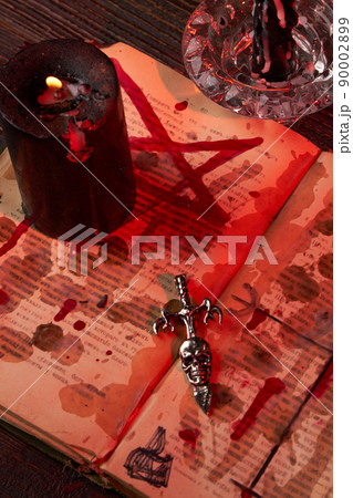 Vertical shot of antichrist cross on the satanic bible stained with blood. 90002899