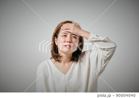 風邪をひいておでこに手を当てる若い女性 90004040