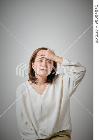 風邪をひいておでこに手を当てる若い女性 90004041