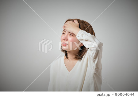 風邪をひいておでこに手を当てる若い女性 90004044