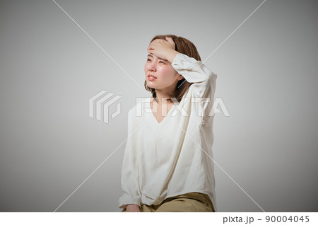 風邪をひいておでこに手を当てる若い女性 90004045