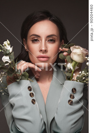 Beautiful brunette girl iwith a gentle romantic make-up, pink lips, holding flowers. The beauty of the face. Beautiful brunette girl iwith a gentle romantic make-up, pink lips, holding flowers. The beauty of the face. 90004460