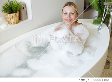 Portrait of young blonde pretty woman smiling and enjoying bubbles in bathtub. Portrait of young blonde pretty woman smiling and enjoying bubbles in bathtub. 90004468