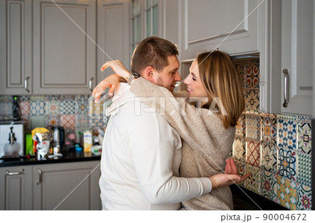a happy and loving couple fooling around and hugging at home in the kitchen  90004672