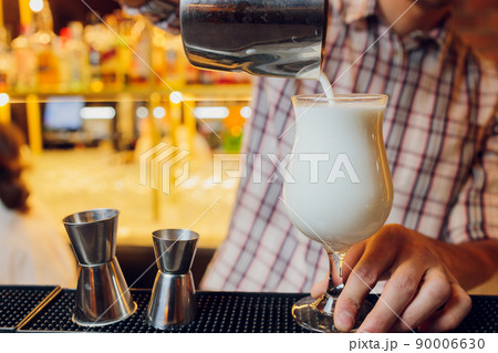 Close up shot of bartender hand pouring Cream mocktail in a glass from shaker. 90006630