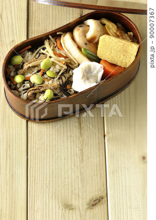 ひじきと枝豆のご飯、シュウマイや玉子焼き、煮物等たくさんのおかずが入っている幕の内弁当を俯瞰で撮影 ひじきと枝豆のご飯、シュウマイや玉子焼き、煮物等たくさんのおかずが入っている幕の内弁当を俯瞰で撮影 90007367