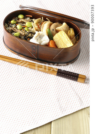 ひじきと枝豆のご飯、シュウマイや玉子焼き、煮物等たくさんのおかずが入っている幕の内弁当 90007393