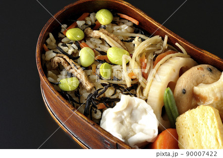 ひじきと枝豆のご飯、シュウマイや玉子焼き、煮物等沢山のおかずが入っている幕の内弁当を黒背景で俯瞰撮影 ひじきと枝豆のご飯、シュウマイや玉子焼き、煮物等沢山のおかずが入っている幕の内弁当を黒背景で俯瞰撮影 90007422