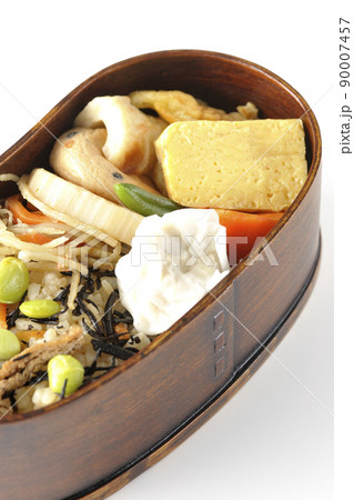 ひじきと枝豆のご飯、シュウマイや玉子焼き、煮物等沢山のおかずが入っている幕の内弁当を白背景で撮影 90007457