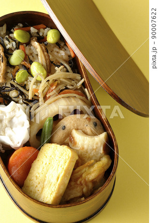 ひじきと枝豆のご飯、シュウマイや玉子焼き、煮物等たくさんのおかずが入っている幕の内弁当を俯瞰で撮影 90007622